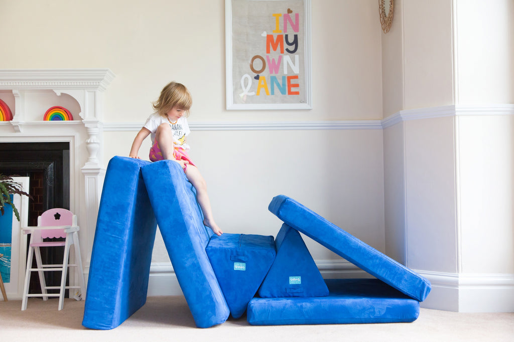 Child in lovely playroom on top of Sofee play sofa about to climb down. 